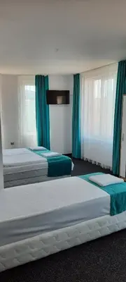 two beds in a hotel room with blue curtains at Къща за гости Вивиан in Kiten