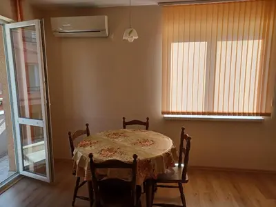 a dining room with a table and chairs and windows at Апартамент Желева in Pomorie