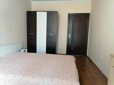 a bedroom with a bed and some wooden cabinets at Апартамент Даскала с паркомясто in Burgas City