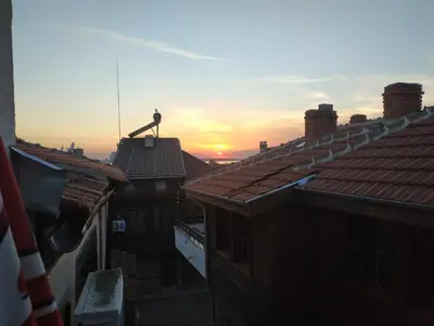 a bird sitting on top of a roof with the sunset at Къщата с разкопките - The house with the excavations in Sozopol
