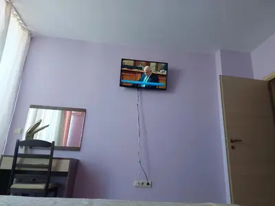 a tv on a white wall in a bedroom at Gradina Sunny Deluxe apartment in Sozopol