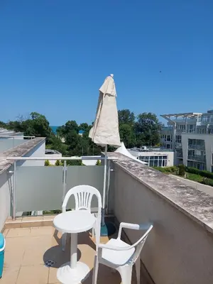 a balcony with two chairs and a table and an umbrella at Gradina Sunny Deluxe apartment in Sozopol