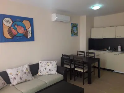 a living room with a couch and a table and a kitchen at Gradina Sunny Deluxe apartment in Sozopol