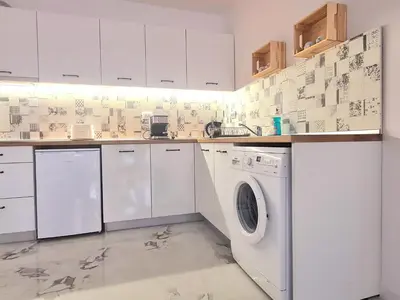 a white kitchen with a washing machine in it at Dolphin beach apart Obzor in Obzor