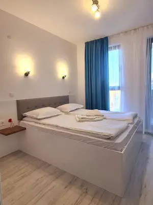 a bedroom with a large bed with a blue curtain at Dolphin beach apart Obzor in Obzor