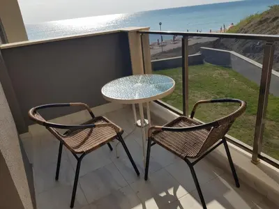 a balcony with a table and two chairs and the beach at Dolphin beach apart Obzor in Obzor