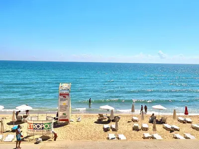 a beach with chairs and umbrellas and the ocean at Gold beach apart Obzor in Obzor