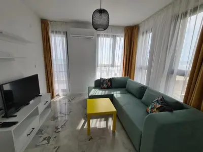 a living room with a green couch and a tv at Gold beach apart Obzor in Obzor
