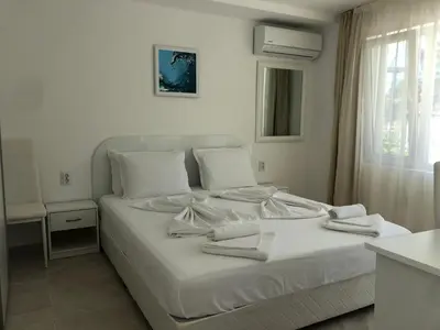 a bedroom with a white bed with towels on it at Borko Guest House in Primorsko