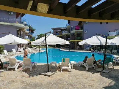 a swimming pool with people sitting in chairs and umbrellas at Casa do Farol - апартамент с басейн до плажа на къмпинг 