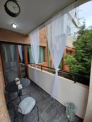 a balcony with a table and chairs and a clock at Tara Deluxe Apartment in Varna City