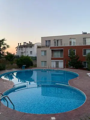 a large blue swimming pool in front of a building at Villa Rouge - Apartment Victoria in Sozopol