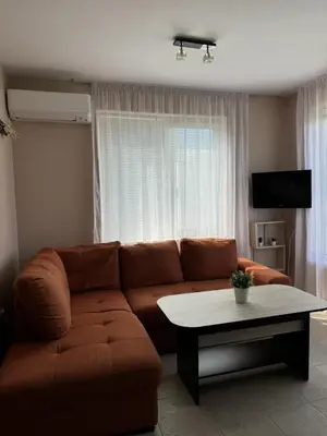 a living room with a brown couch and a table at Villa Rouge - Apartment Victoria in Sozopol