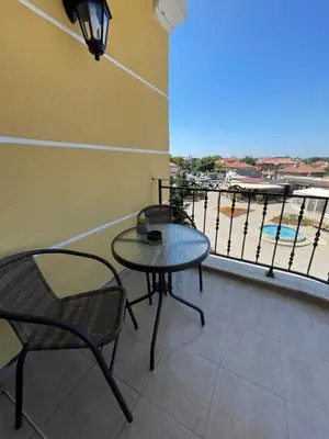 a balcony with two tables and chairs and a view of a harbor at Chernomorets Apartment in Chernomorets