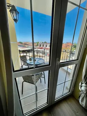 a room with a balcony with a table and a glass door at Chernomorets Apartment in Chernomorets