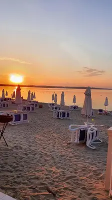 a beach with chairs and umbrellas at sunset at Eve Santa Marina Apartments - sea, pools, relax in Sozopol