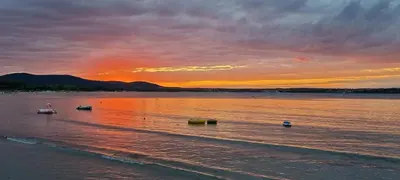 a sunset on a beach with boats in the water at Eve Santa Marina Studios - sea, pools, relax in Sozopol