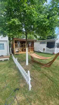 a hammock in front of a house with a tree at Каравана Амалтея in Sozopol
