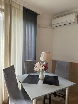 a white table with chairs and a vase of flowers on it at Студио ''Сарафово'' на първа линия in Burgas City