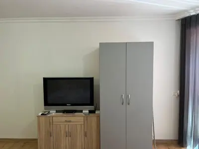 a living room with a television on a wooden cabinet at Студио ''Сарафово'' на първа линия in Burgas City