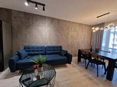 a living room with a blue couch and a table at Marsselis Luxe Port Apartment in Varna City