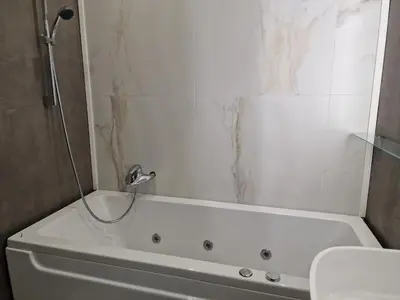 a white bath tub with a shower in a bathroom at Marsselis Luxe Port Apartment in Varna City