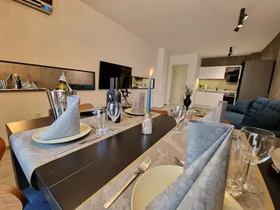 a dining room with a table with plates and wine glasses at Marsselis Luxe Port Apartment in Varna City