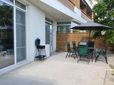 a patio with a table and chairs and an umbrella at Las Brisas Garden Apartment in Burgas City
