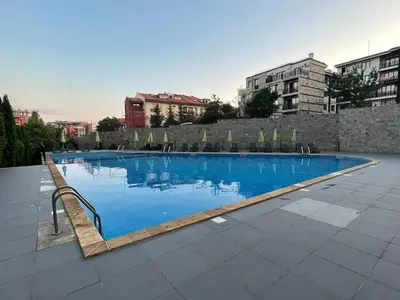 a large blue swimming pool with chairs and buildings at HELIOS I premium in Sveti Vlas