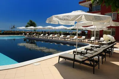 a pool with chairs and umbrellas next to a hotel at Heaven Lux Apartments in Sunny Beach