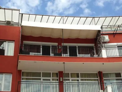 an external view of a red building with a balcony at Heaven Lux Apartments in Sunny Beach
