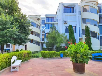 a building with a white bench in front of it at Sveti Vlas Marina Beach Apartment - Vega Village in Sveti Vlas