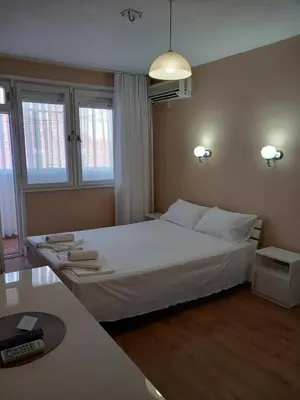a bedroom with a large white bed and two windows at Апартамент Морски оазис in Burgas City