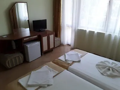 a room with two beds and a desk and a television at Kostovi Primorsko in Primorsko