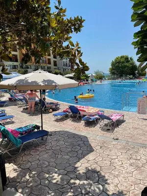 a pool with chairs and umbrellas and people in the water at Marina Cape SP private apartments in Aheloy