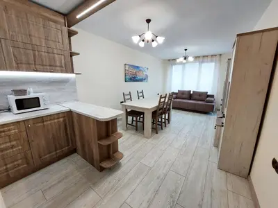 a kitchen and dining room with a table with a microwave at Апартаменти за гости Делукс in Burgas City