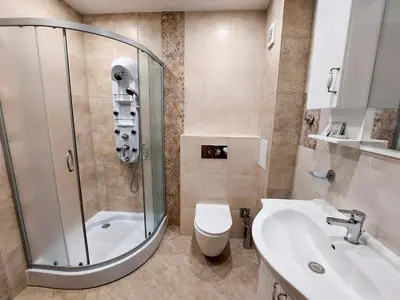 a bathroom with a shower and a toilet and a sink at Апартаменти за гости Делукс in Burgas City