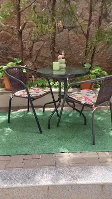 a black table and two chairs on a green rug at Венета 1 in Sozopol