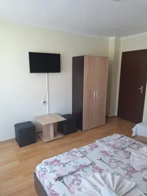 a bedroom with a bed and a table and a cabinet at Къща за гости Симеонови in Sozopol
