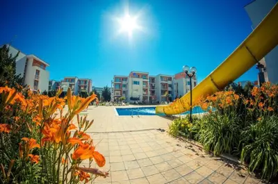a swimming pool with orange flowers in front of buildings at 1-bedroom Apartment in a Resort with 6 Pools, Top Floor, Stunning Sunset View in Sunny Beach