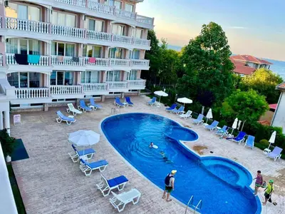 a hotel with a swimming pool with chairs and umbrellas at Perla Del Mar Studio PANORAMA First line in Lozenets