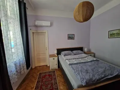 a bedroom with a bed and a large window at Етаж от къща с двор in Burgas City