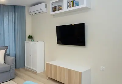 a living room with a couch and a tv on a wall at The Blue Apartment - 1BD with a Cozy Balcony by Flat Mаnager in Varna City