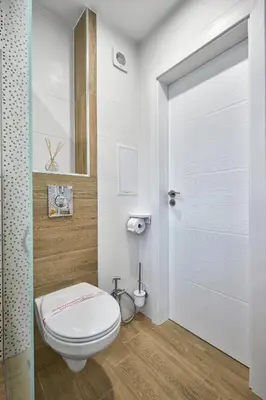 a bathroom with a white toilet and a door at Weiss Estate by EstateAutomata in Burgas City