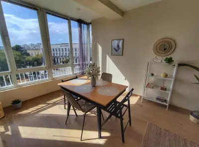 a table and chairs in a room with large windows at By The Cathedral, 1 bed flat in Varna City