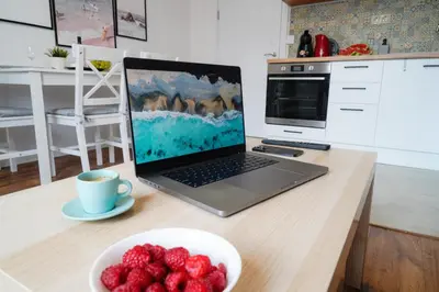 a laptop computer sitting on a desk with a bowl of strawberries at Central Cosy, Fully Renovated 2BD Near the Cathedral in Varna City