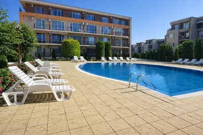 a pool with white lounge chairs next to a building at Nice family apartment in Sunny Beach