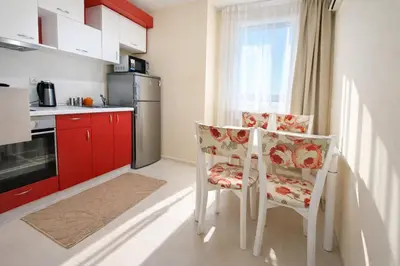 a kitchen with red cabinets and a table and chairs at Nice family apartment in Sunny Beach