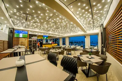 a restaurant with tables and chairs and lights on the ceiling at Premier Fort Beach Hotel in Sveti Vlas