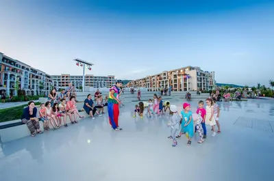 a group of children sitting around a man in a crowd at Premier Fort Beach Hotel in Sveti Vlas